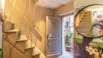 Una escalera con una escalera de cuerda, una puerta cerrada y un mural con un árbol y flores.
