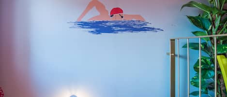 A wall with a swimmer silhouette, a hanging light fixture, and a potted plant.