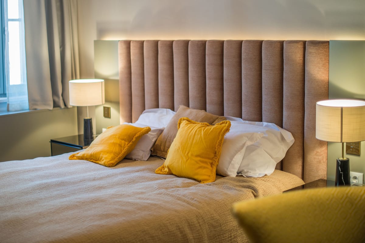 A hotel room with a large bed, two bedside lamps, and a window with curtains.
