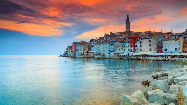 A coastal town with colorful buildings, a prominent tower, and calm waters. - The Melegran (Rovinj)