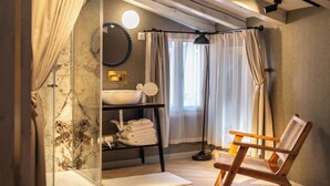 A bathroom with a marble sink, a mirror, a towel rack, and a chair. - The Melegran (Rovinj)