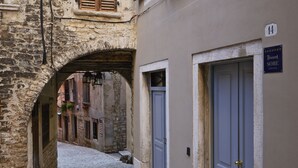 A narrow cobblestone street with stone buildings, a wooden door, and a sign with the number 14. - The Melegran (Rovinj)