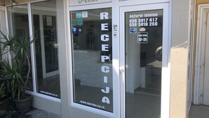 A hotel reception area with a sign reading "RECEPTION" and a directory listing phone numbers.