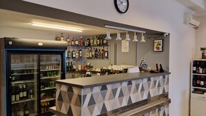 A bar area with a patterned counter, a clock, and shelves of liquor bottles.