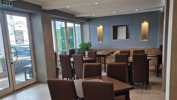 A spacious dining area with multiple tables and chairs, large windows, and a modern interior design.