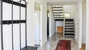 A hallway with a black metal rack, a wooden bench, a staircase with black steps, and a patterned rug. - Beautiful home in Säffle with kitchen (Säffle)