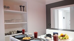 Una cocina moderna con zona de desayuno que incluye platos, vasos y un frutero.
