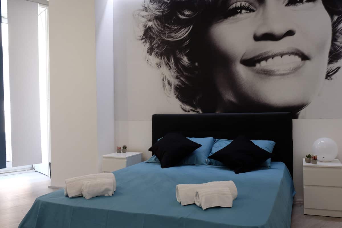 A bedroom with a bed, pillows, and a nightstand.