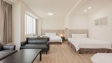 Quarto de hotel com duas camas, um sofá, uma mesa e uma janela com cortinas.