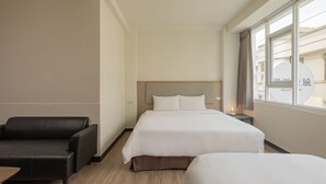 A hotel room with a large bed, a sofa, a small table, and a window with curtains. - Meant to Be (Chiayi City)