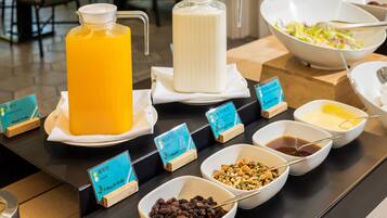 Una mesa de buffet con diversos alimentos y dispensadores de bebidas.