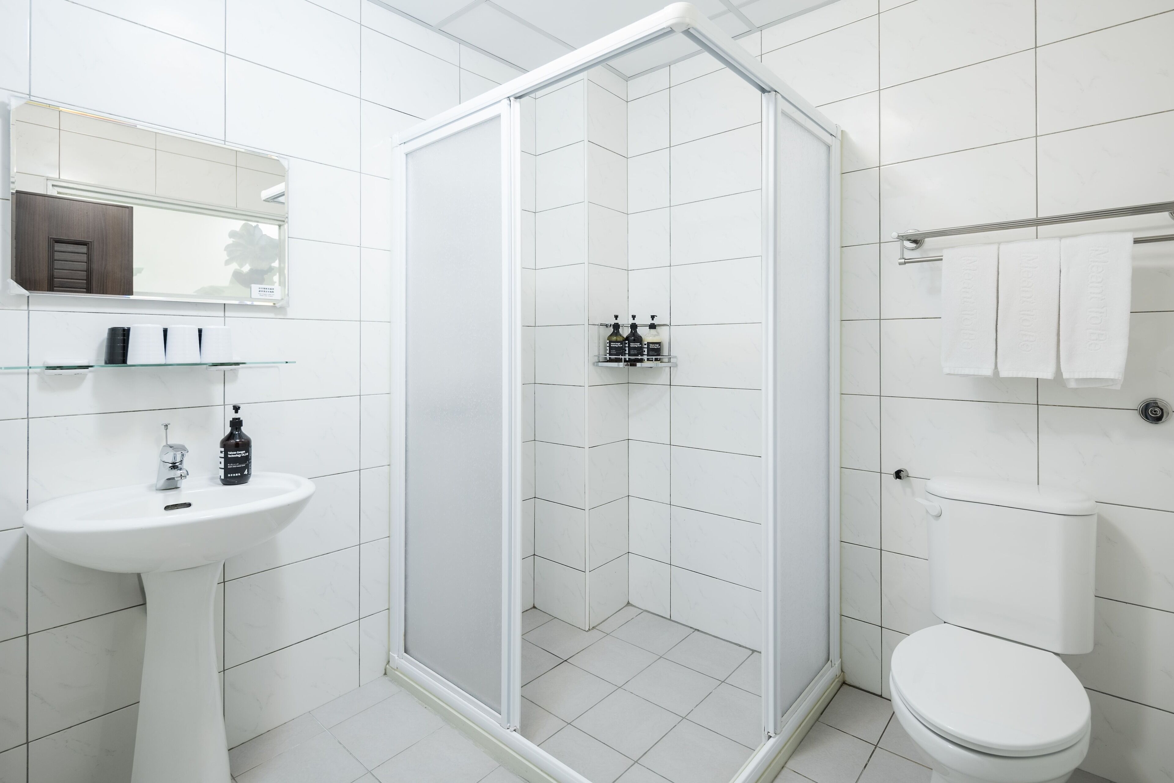 Moderni kylpyhuone, jossa on valkoinen pesuallas, lasinen suihkuseinä ja wc-istuin.