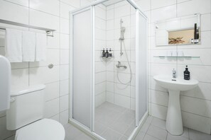A modern bathroom with a glass-enclosed shower, a white pedestal sink, and a toilet. - Meant to Be (Chiayi City)