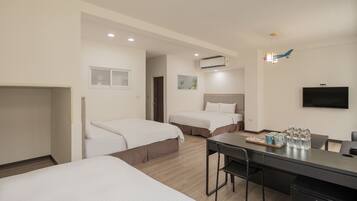 A hotel room with two beds, a desk with a chair, a television, and a minibar.
