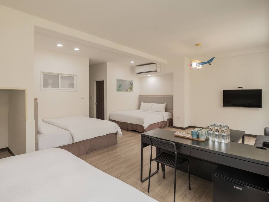 A hotel room with two beds, a desk with a chair, a television, and a minibar.