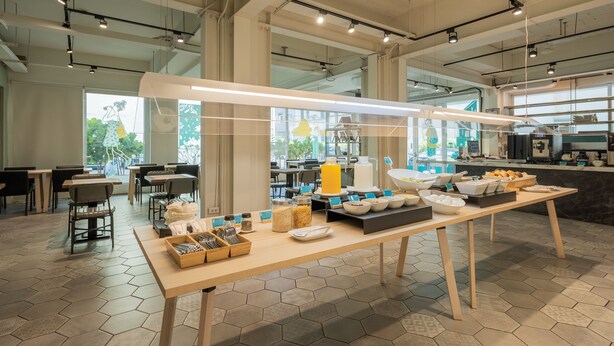 A modern dining area with hexagonal tiles, a long table with breakfast items, and a kitchen in the background. - Meant to Be (Chiayi City)