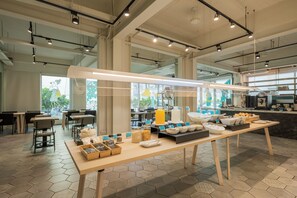 A modern dining area with hexagonal tiles, a long table with breakfast items, and a kitchen in the background. - Meant to Be (Chiayi City)