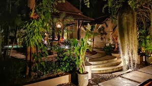 A nighttime garden with a gazebo, stone steps, and various plants. - Montra Samui (Koh Samui)