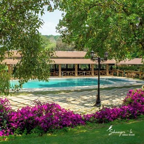 Zona de piscina con una zona de estar cubierta y un farol.