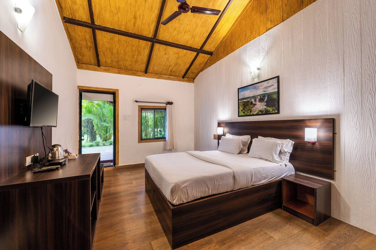 A modern bedroom with a wooden ceiling, a large bed, a TV, and a desk.