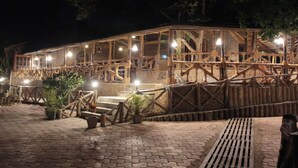 Un edificio de madera con un patio cubierto, plantas en macetas y una valla de madera.