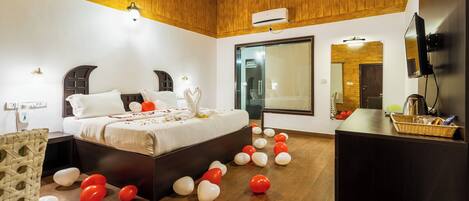 A bedroom with a bed, wooden ceiling, and a TV on a stand.