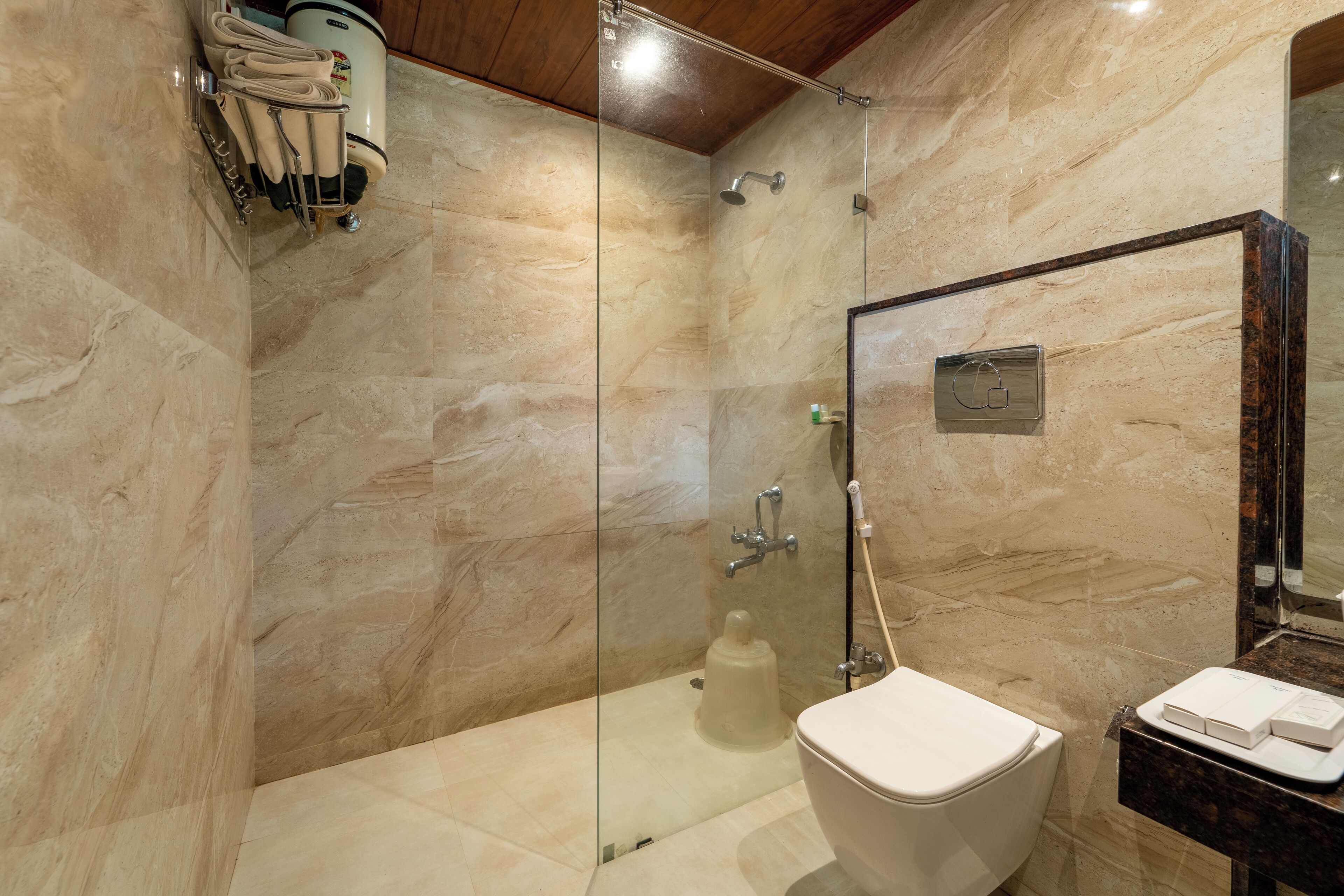 A modern bathroom with a glass-enclosed shower, a white toilet, and a marble wall.