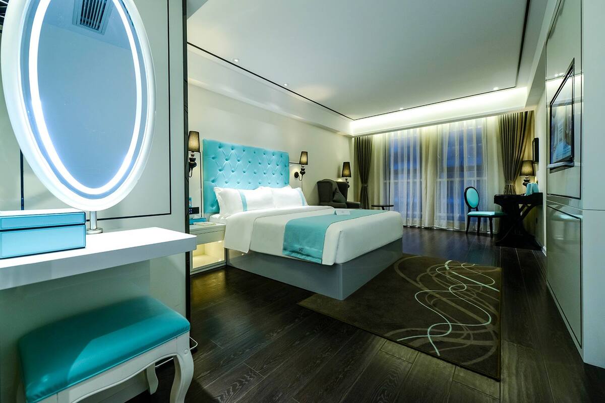 Ein modernes Hotelzimmer mit einem großen Bett, einem Nachttisch, einem Spiegel und einer Sitzecke mit einem Sessel.