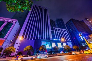 A high-rise building with multiple floors, large windows, and a prominent advertisement on the facade. - Xana Hotelle In Guanyinqiao Of Chongqing (Chongqing)