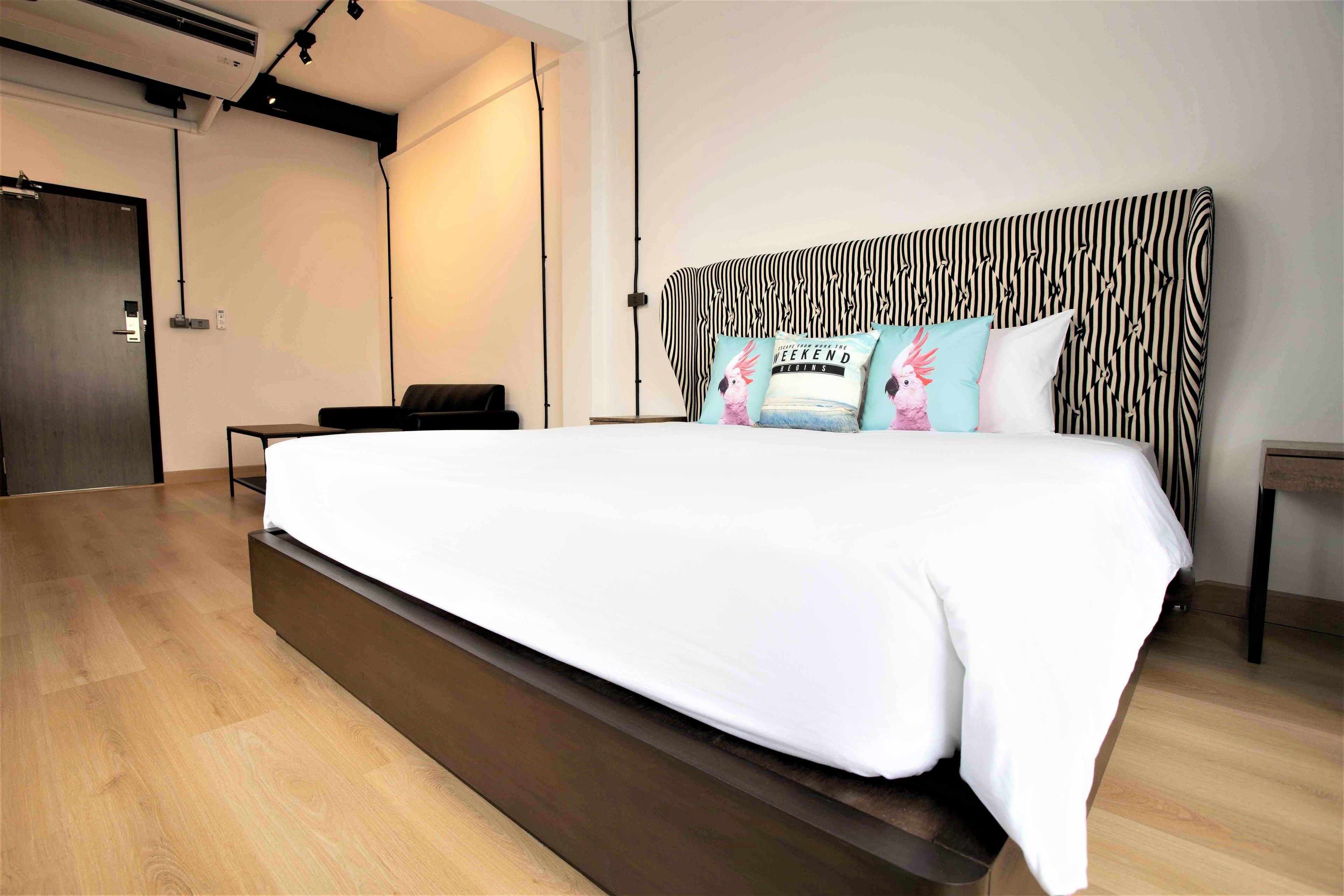 A modern hotel room with a large bed, a small desk, and a wardrobe.