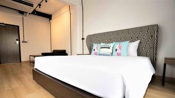 A modern hotel room with a large bed, a small desk, and a wardrobe.
