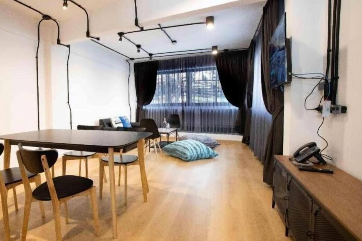 Una habitación moderna con una mesa de comedor, sillas, un sofá y un televisor montado en la pared.