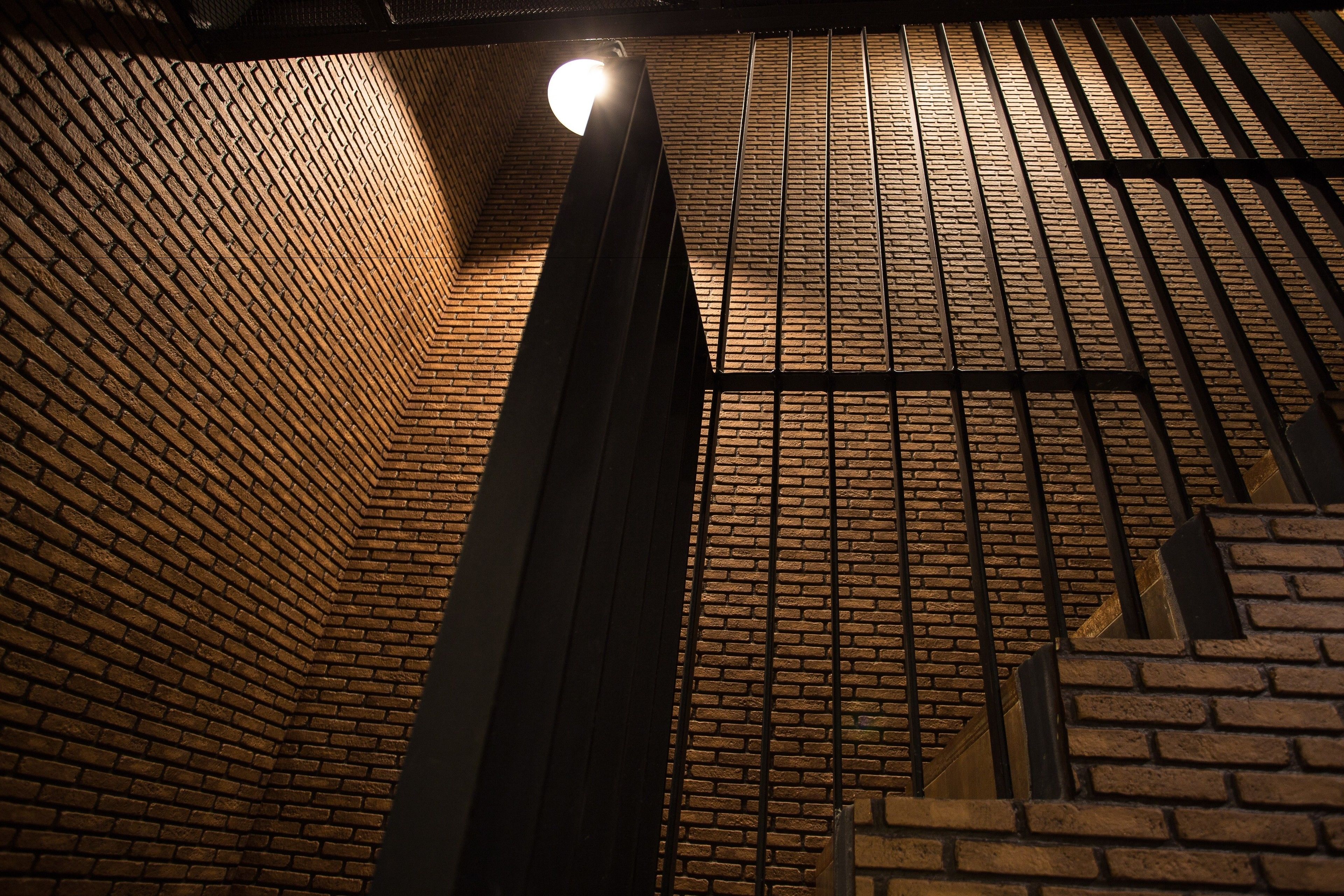 A brick wall with a metal railing and a light fixture.
