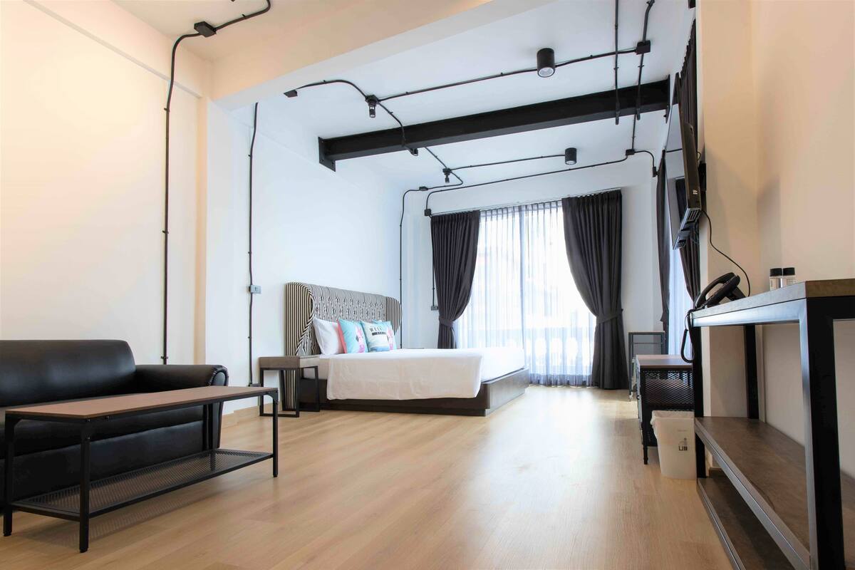 Una habitación de hotel moderna con una cama, un sofá, un escritorio y un televisor.