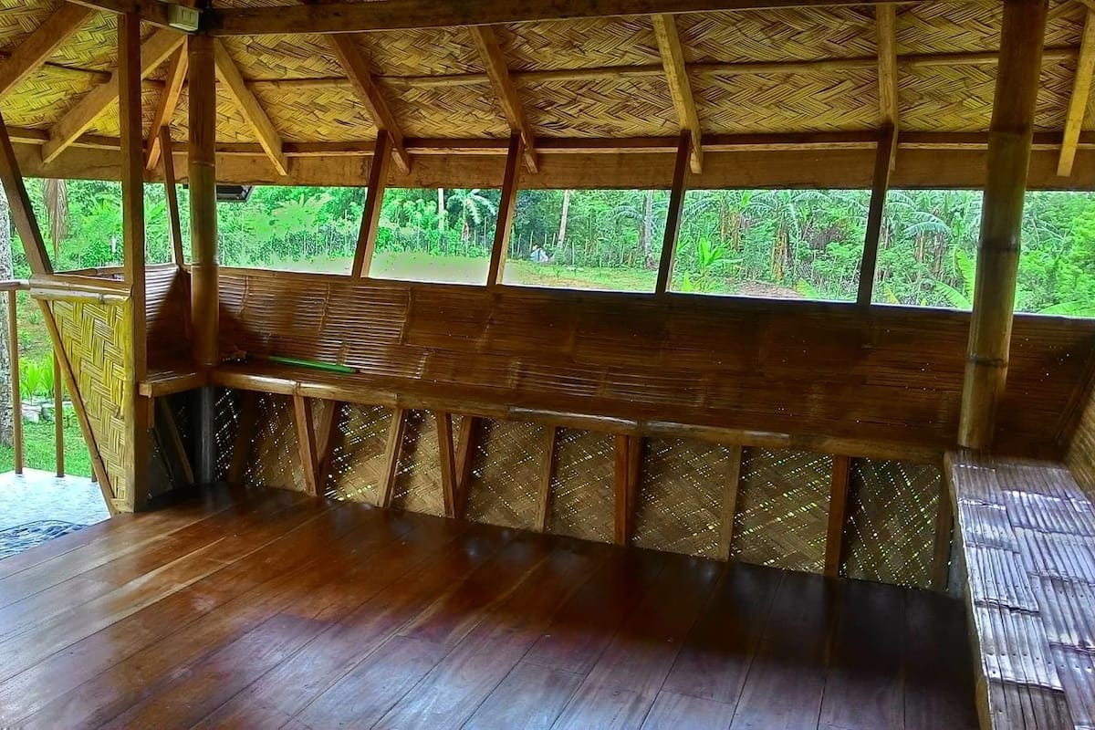A wooden structure with a bench and a thatched roof.