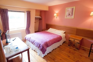 A bedroom with a bed, bedside table, lamp, and a small wooden chest. - Setanta B&B (Ardee)