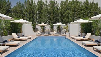 Alberca al aire libre, sombrillas en la alberca y camastros