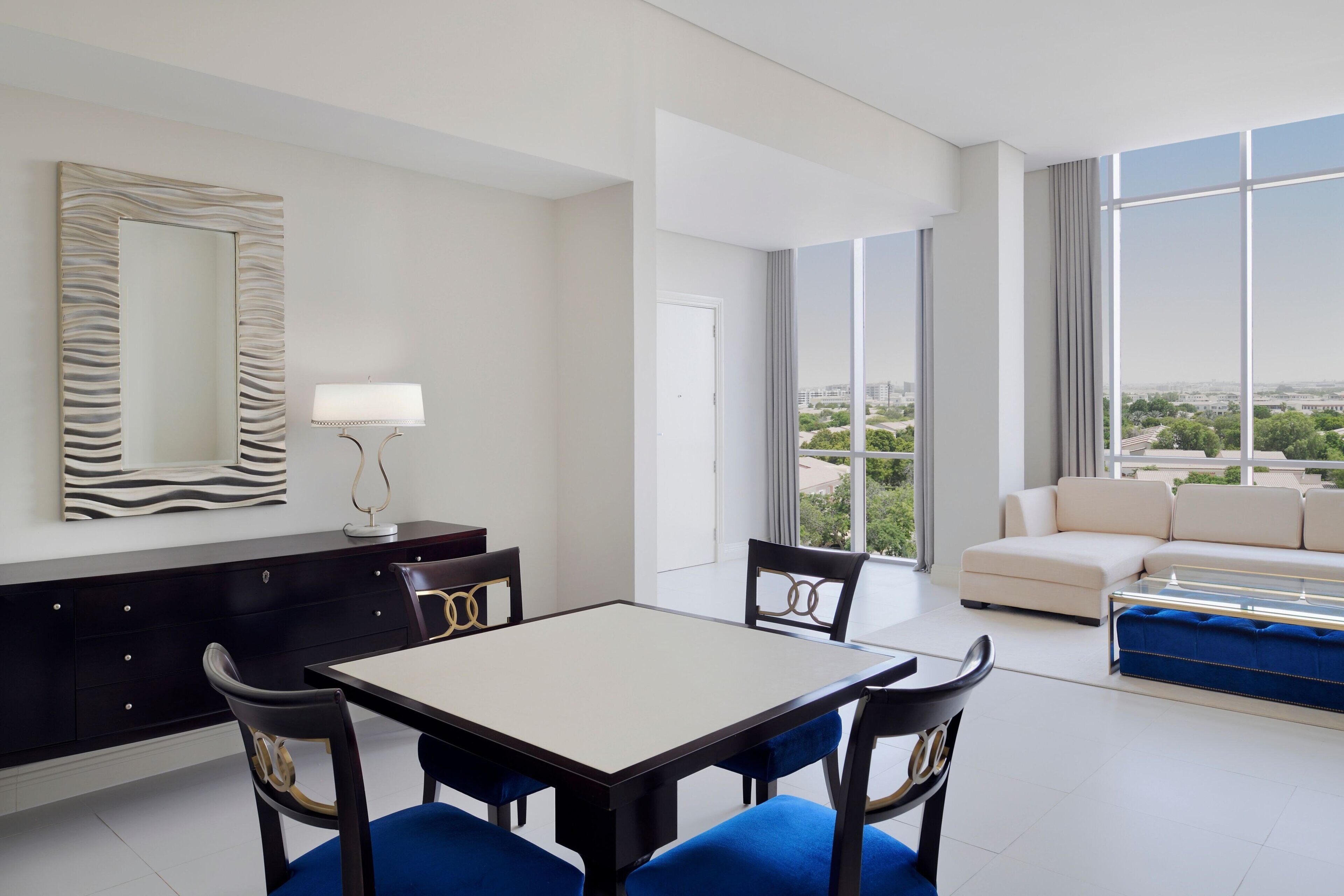 Ein modernes Hotelzimmer mit Essbereich, einer Sitzecke und großen Fenstern mit Blick auf die Stadt.