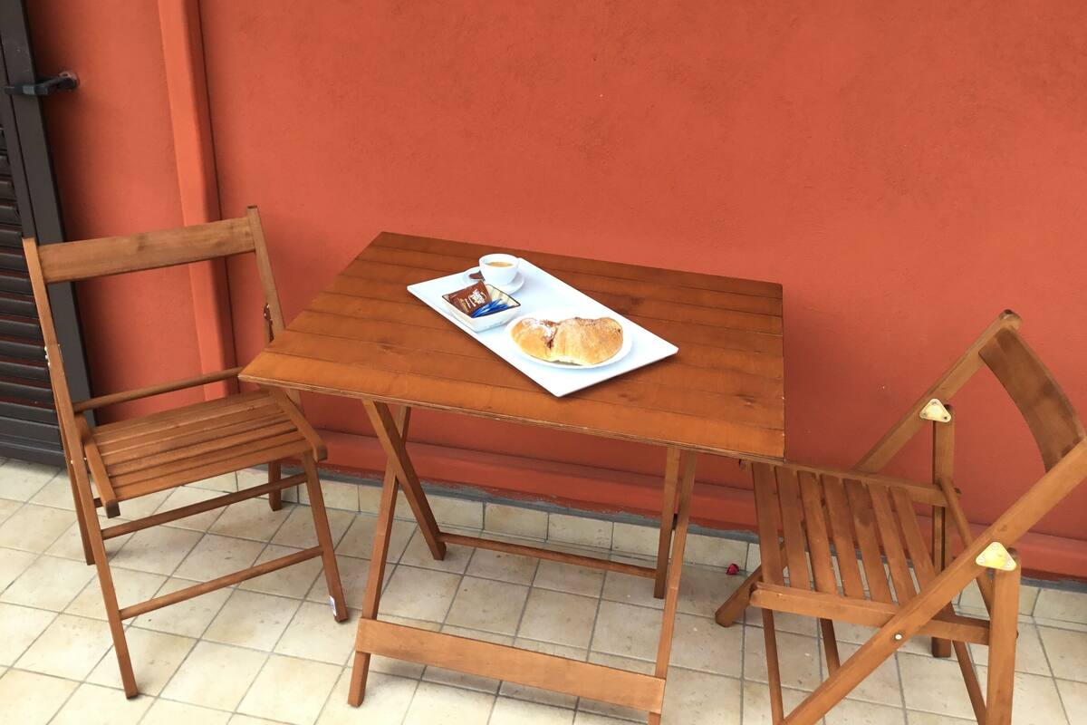 Une table en bois, sur laquelle se trouvent un plateau de nourriture et une tasse, le tout placé devant un mur rouge.