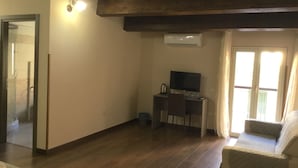 Een kamer met houten vloer, een bureau met televisie, een stoel en een raam met gordijnen.