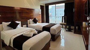 Ein Hotelzimmer mit zwei Betten, einem Fernseher und Blick auf die Stadt.