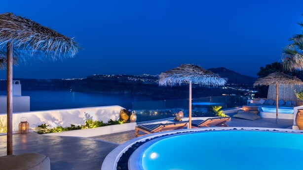 A poolside area with lounge chairs, umbrellas, and a view of the sea at dusk. - Summer Lovers Villa (Santorini)