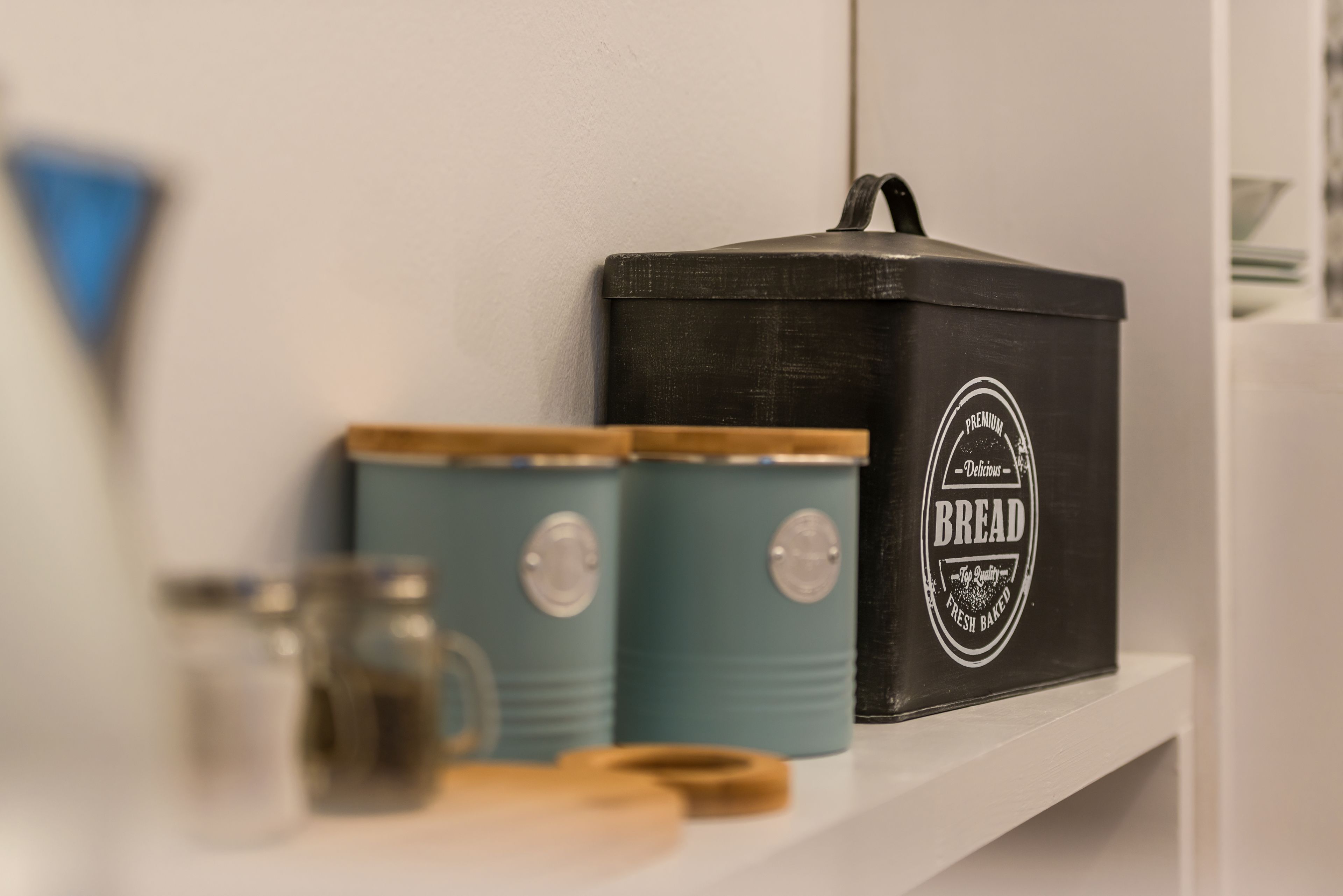 Ein Küchenregal mit einer schwarzen Brokasten und zwei türkis-farbenen Behältern.