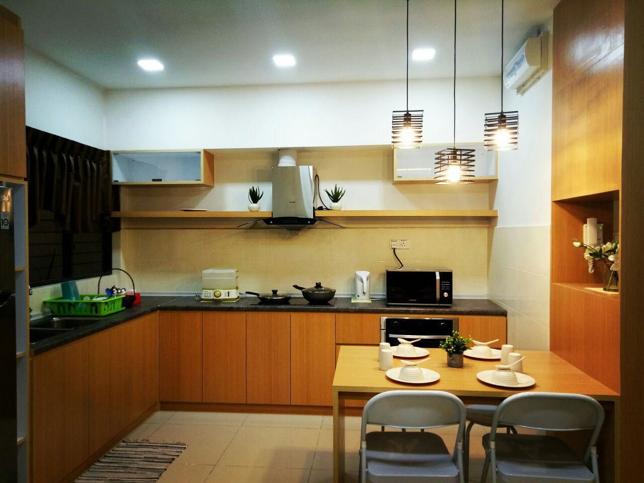 Uma cozinha compacta com armários de madeira, uma mesa de jantar com cadeiras e luminárias pendentes.