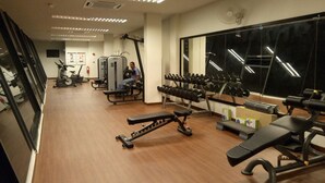 A gym with exercise equipment, a mirror, and a person working out. - Greenfield Residence Kota Kinabalu (Kota Kinabalu)