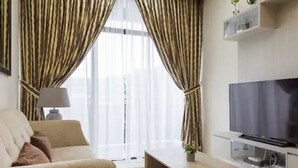 A living room with a sofa, a flat-screen TV, a coffee table, and curtains. - Greenfield Residence Kota Kinabalu (Kota Kinabalu)