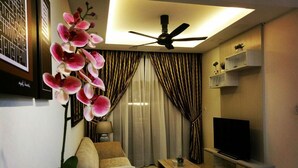 A modern living room with a sofa, coffee table, TV, and decorative plants. - Greenfield Residence Kota Kinabalu (Kota Kinabalu)