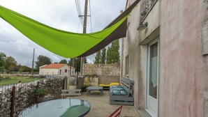 Une terrasse avec une table en verre, un banc rembourré et un hamac.