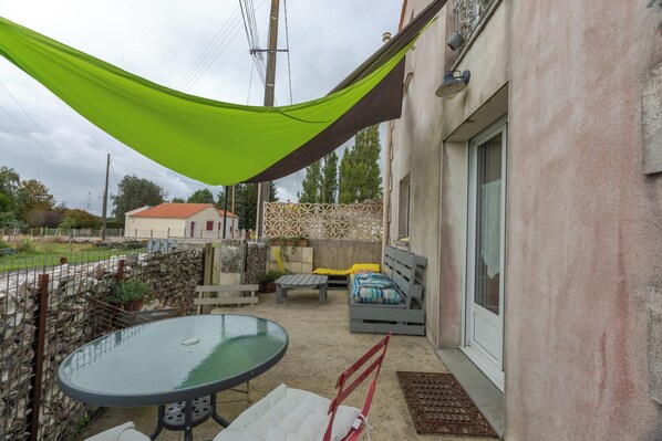 A patio with a glass table, a cushioned bench, and a hammock.