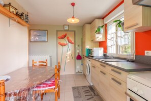 Une cuisine équipée d’une table à manger, de chaises, d’un lave-linge, d’un four à micro-ondes et d’un évier.